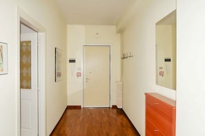 A hallway with a wooden floor, a white door, a radiator, and a dresser with drawers. - Bright 105 m² apartment on the fifth floor, in a quiet residential area of Pescara. Sleeps up to 6 guests with two bedrooms, a sofa bed in the living room and two bathrooms. Fully equipped kitchen, dishwasher, washing machine, air conditioning and Wi-Fi (Pescara)