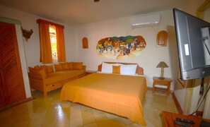 Una habitación de hotel con una cama, un sofá, un televisor y un mural en la pared.