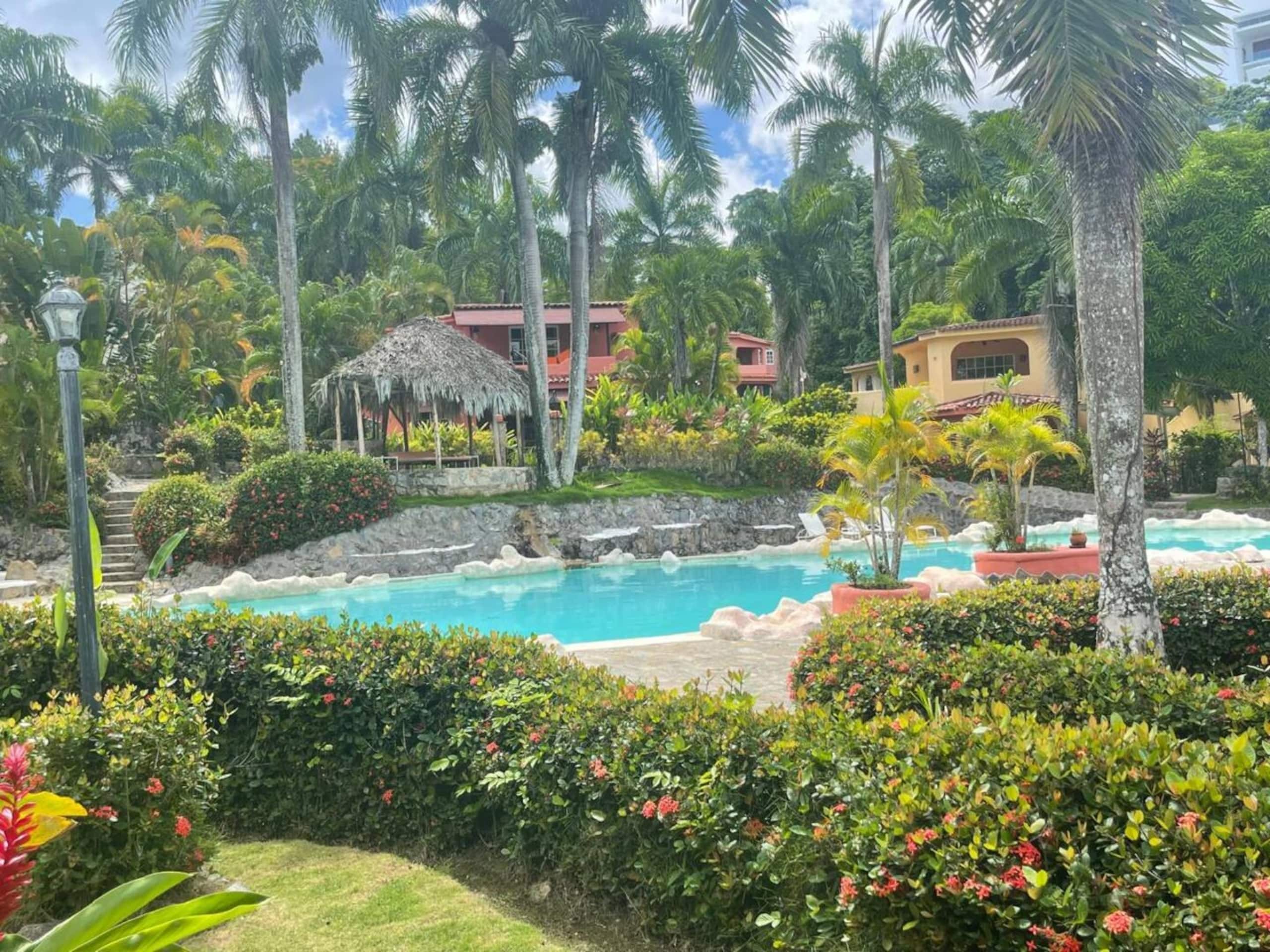 Un resort con piscina rodeada de vegetación tropical y palmeras.