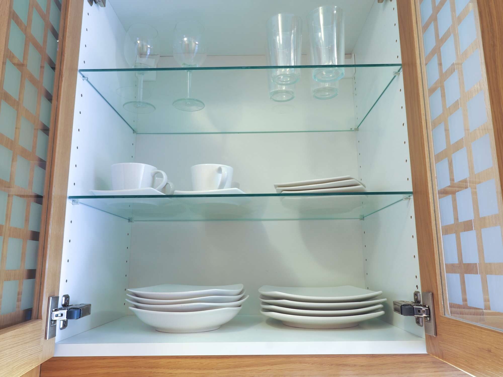 Ein Schrank mit drei Einlegebögen, auf denen verschiedene Gegenstände stehen.