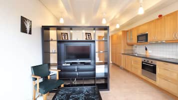 Eine moderne Küche mit integriertem Fernseher, Holzschränken und einer Marmorarbeitsplatte.