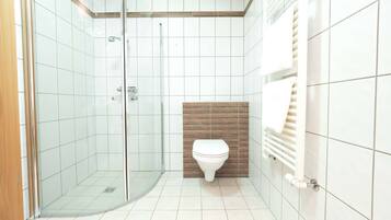 Ein modernes Badezimmer mit einer gläsernen Dusche, einer Toilette und einem Handtuchhalter.
