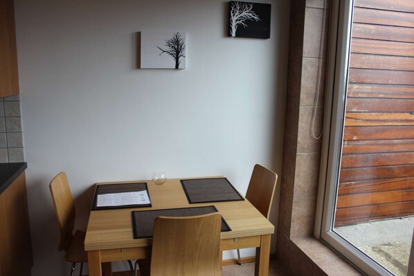 Comedor con mesa de madera, cuatro sillas, un vaso y dos obras de arte en la pared.