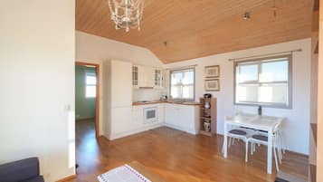 A spacious kitchen with wooden cabinets, a dining area with a table and chairs, and a chandelier.