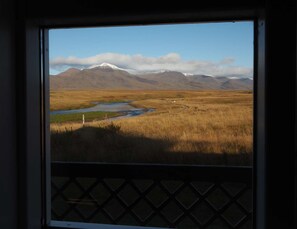 Vista de un paisaje montañoso con un río y una valla en primer plano.