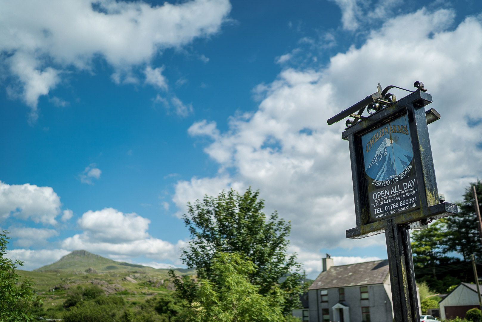 A pub sign with a mountain view in the background.