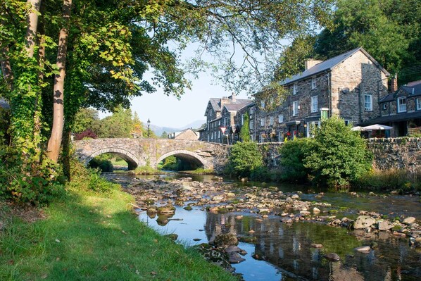 A stone bridge over a river with a stone building on the right.