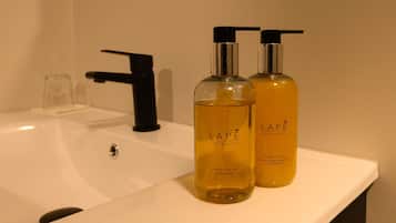 Ein Badezimmer mit einem weißen Waschbecken, zwei Flaschen Handseife aus der LAPE-Kollektion und einem schwarzen Wasserhahn.