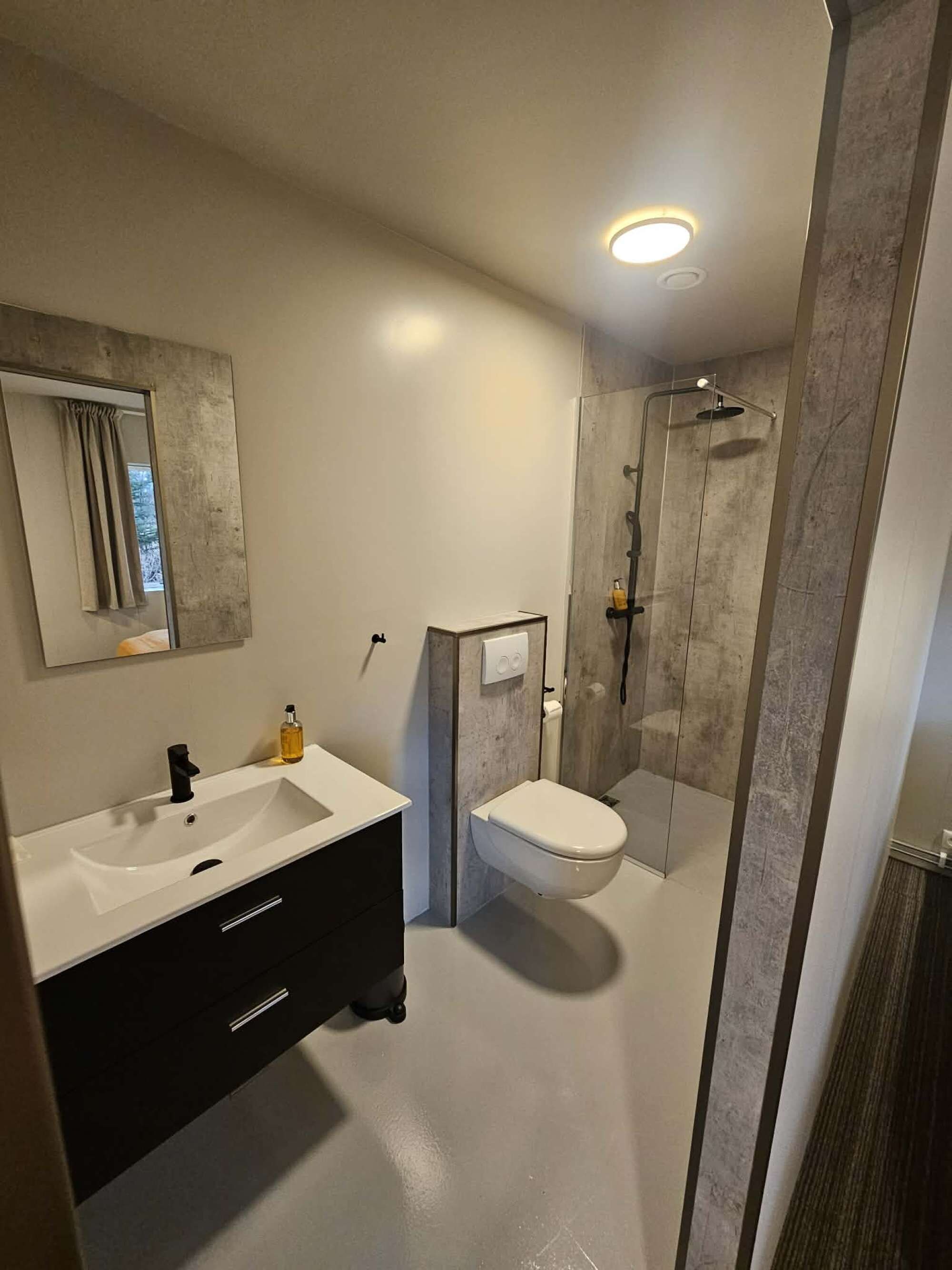 A modern bathroom with a white sink, a toilet, and a glass-enclosed shower area.