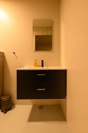 A bathroom with a white sink, black cabinet, and a mirror above it.