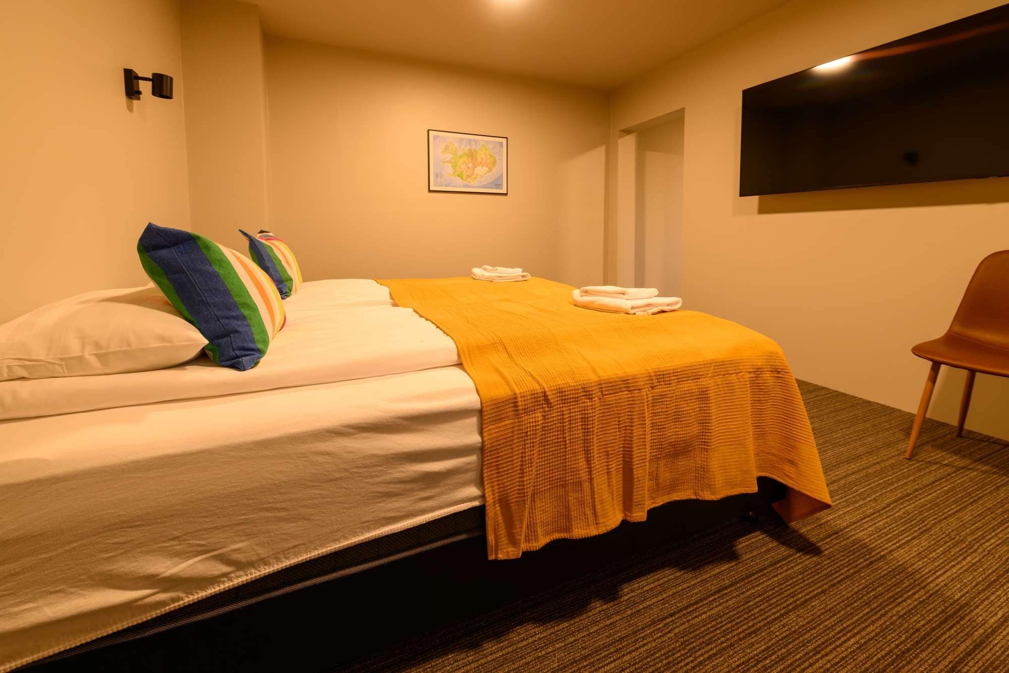 Ein Hotelzimmer mit einem Bett, Kissen, einer Decke, einem Flachbildfernseher und einem Sessel.