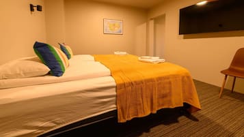 Ein Hotelzimmer mit einem Bett, Kissen, einer Decke, einem Flachbildfernseher und einem Sessel.