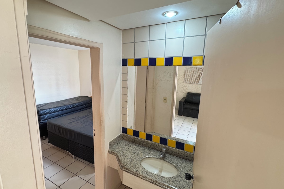 A bathroom with a bed, a sink, and a mirror.