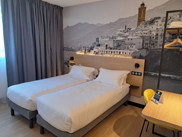 Une chambre d’hôtel avec deux lits, une tête de lit en bois, une fresque murale, une table et une chaise.