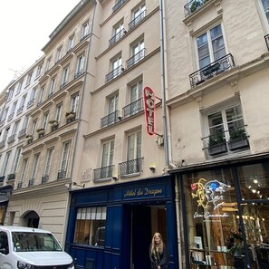 Ein Hotel mit auffälliger roter Signage, blauem Eingang und einer Fassade mit Neonreklame.