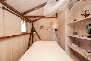 A wooden room with a bed, a window, a shelf with decorative items, and a hanging light fixture. - The Adelaide Lodge - Nature & Tranquility (Cahuzac-sur-Vère)