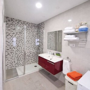 Une salle de bain moderne avec une douche à parois de verre, un meuble-lavabo avec un miroir et un porte-serviettes avec des serviettes pliées.
