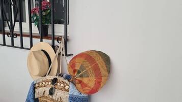 A wall-mounted hat rack with a woven basket and a denim jacket.