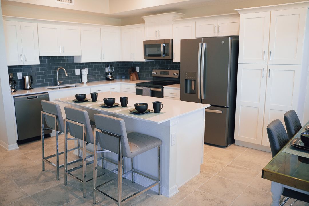 A modern kitchen with white cabinets, stainless steel appliances, and a central island with bar stools.