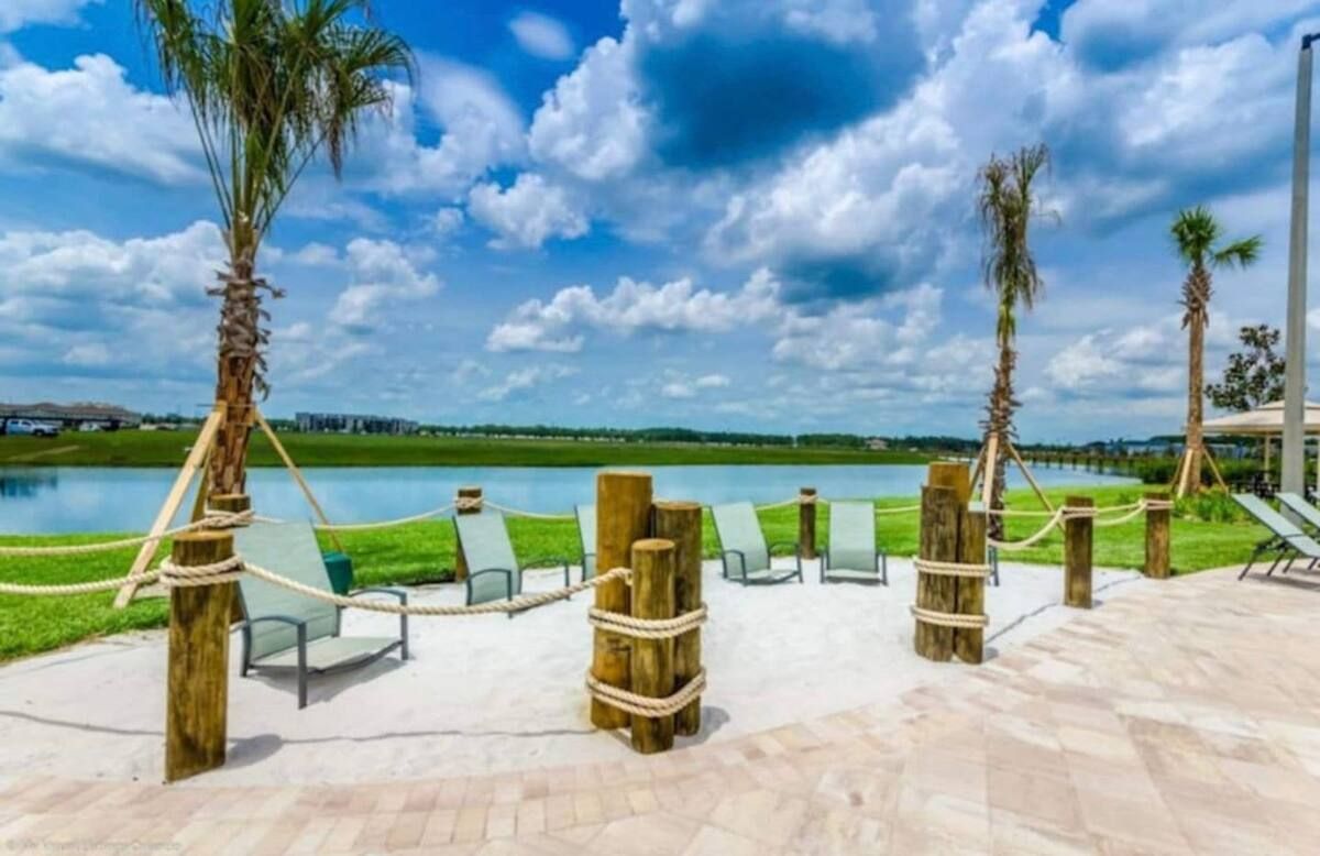 A waterfront patio with lounge chairs and a rope barrier.