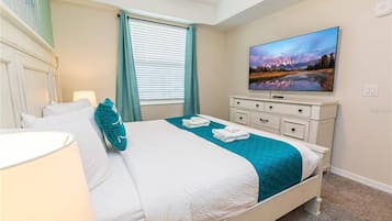 A hotel room with a bed, a television, a dresser, and a window with curtains.