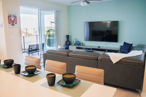 Una sala de estar moderna con un televisor de pantalla plana, un sofá y un comedor con tazones de sopa.