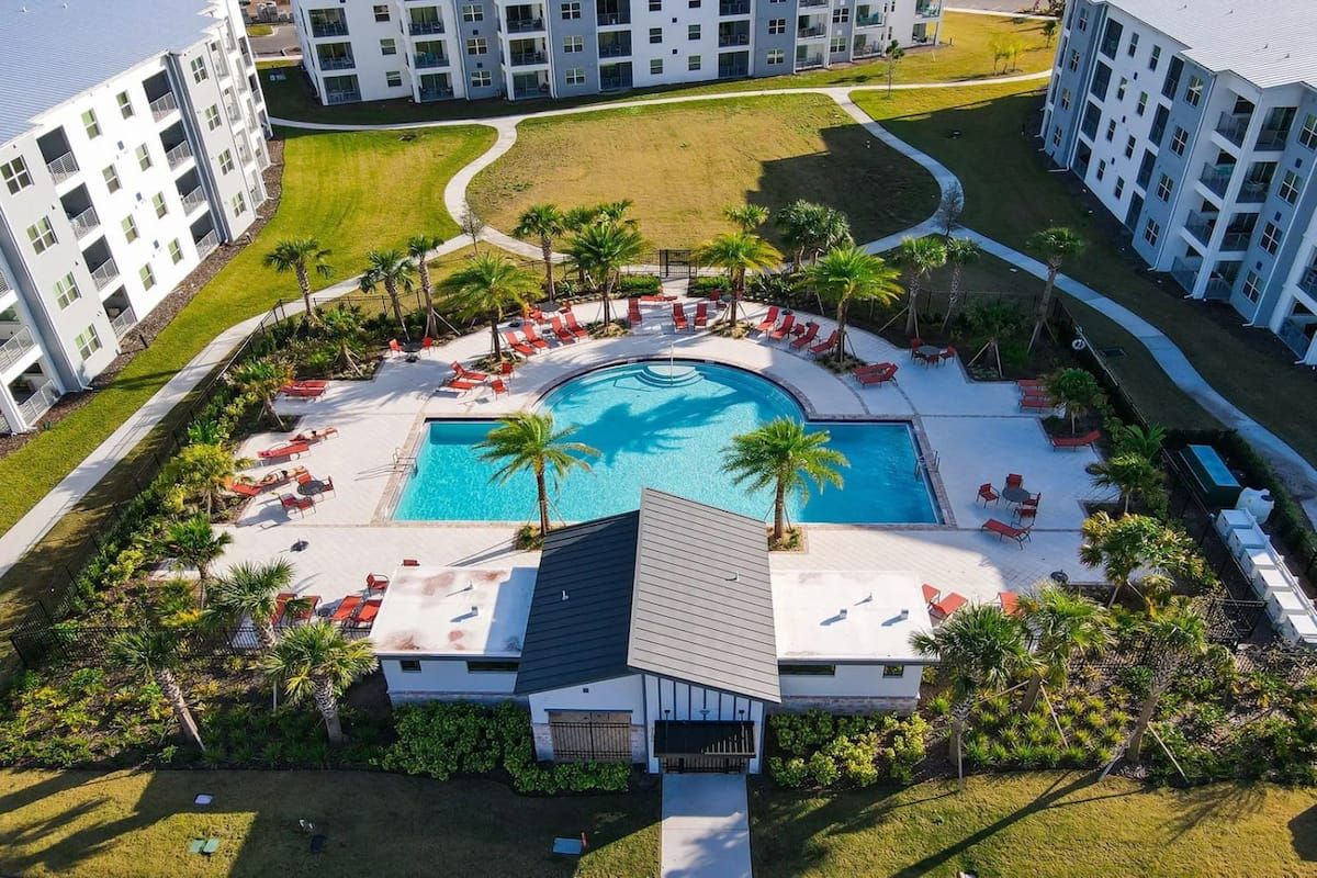 Ein Resort mit einem zentralen Schwimmbecken, umgeben von Liegestühlen und Palmen.