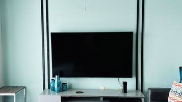 A living room with a flat-screen TV, a ceiling fan, a coffee table, a sofa, and a side table.
