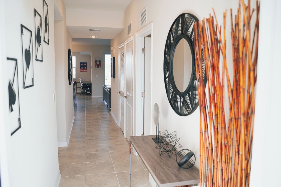 A hallway with framed artwork on the walls, a mirror, and a decorative bamboo arrangement.