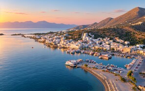 A coastal town with a marina, buildings, and mountains in the background. - Casa Euphoria Private Pool (Schisma Elountas)