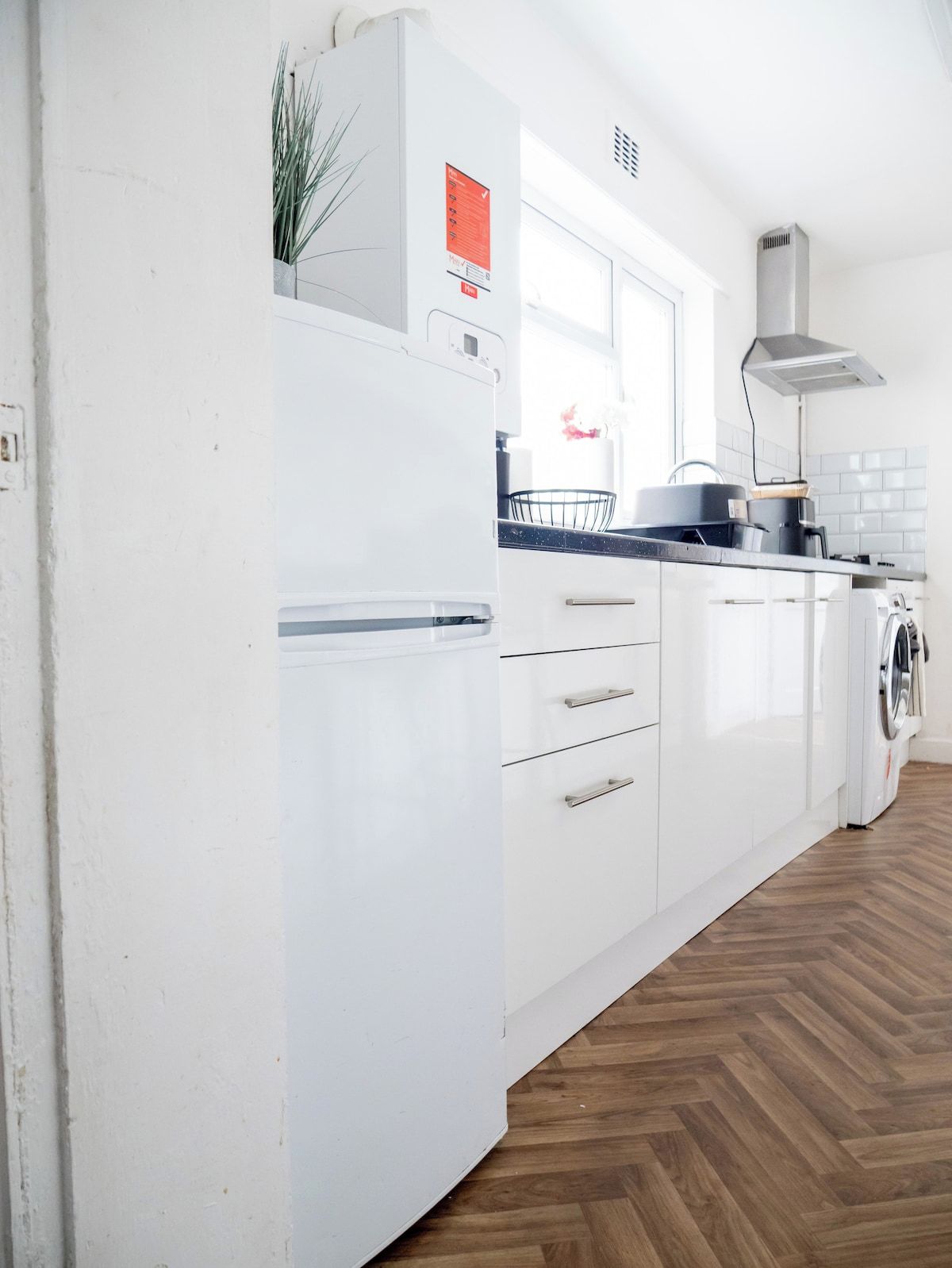 A modern kitchen with white cabinets, a built-in oven, a microwave, and a stainless steel range hood.