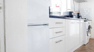 A modern kitchen with white cabinets, a built-in oven, a microwave, and a stainless steel range hood.