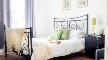 Quarto com uma cama, mesa de cabeceira, luminária e duas fotos emolduradas na parede.