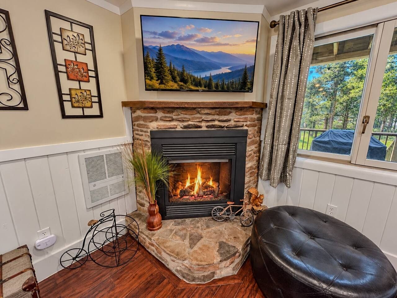 A fireplace with a stone surround, a mounted television above it, and a window with curtains.