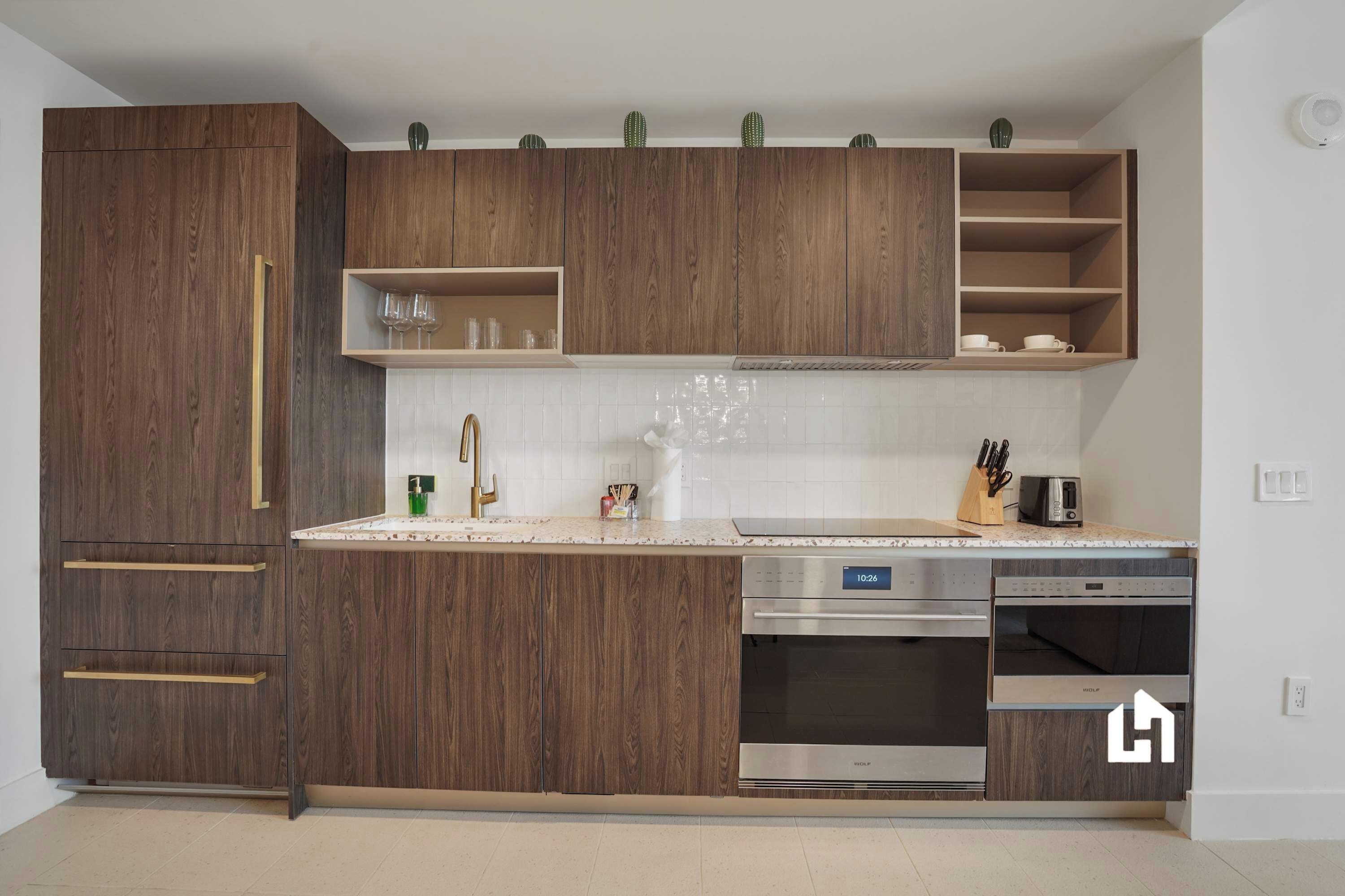 A modern kitchen with wooden cabinets, a stainless steel dishwasher, and a built-in oven.