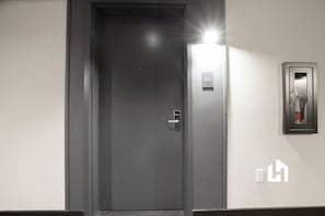 A closed door with a doorbell and a fire alarm panel on the wall. - 37th Floor Studio: Ocean Views & Pool Access (Miami)