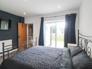 Ein Schlafzimmer mit Bett, Kleiderschrank, einer Tür und Blick ins Freie.