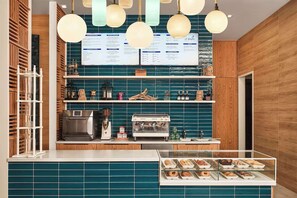 Ein Café mit einer Kaffeemaschine, Regalen voller Snacks und einer Speisekarte.
