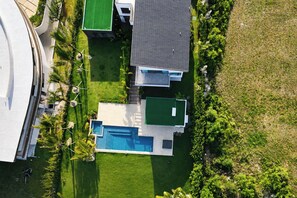 Vista aérea de una zona residencial con piscina, césped verde y casas modernas.
