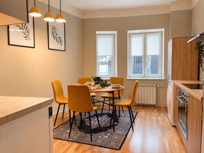 A modern kitchen with wooden cabinets, a built-in oven, and a dining area with a round table and yellow chairs. - 2-Bedroom apartment in the Hart of the city (Tallinn)