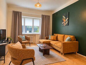 A living room with a sofa, armchair, coffee table, and a television. - 2-Bedroom apartment in the Hart of the city (Tallinn)