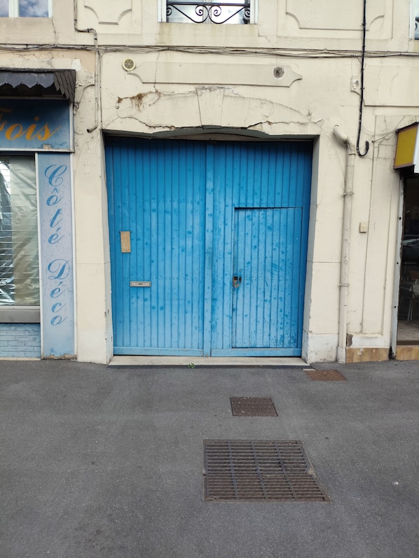 A building facade with a blue door, a metal vent, and a sign with the word 'Café' partially visible.