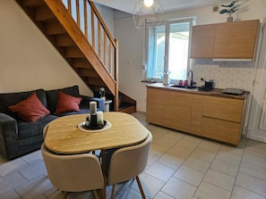 A modern kitchen with wooden cabinets, a dining area with a round table, and a staircase.