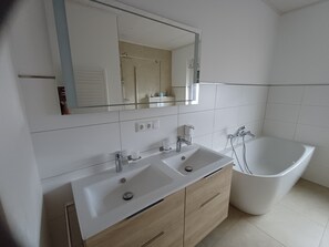 Un bagno con lavabo doppio, una vasca e uno specchio sopra il lavabo.