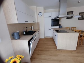 A modern kitchen with white cabinetry, a built-in oven, and a microwave.