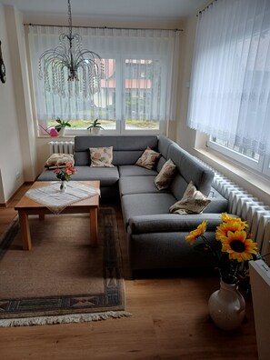 A modern living room with a grey sofa, a wooden coffee table, and a vase with sunflowers.