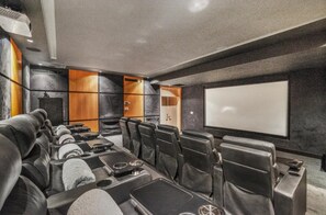 A home theater room with a large screen, leather seating, and a sound system. - Catalina 6: Luxury retreat w/ pool, cinema, gym, golf carts & staff (Casa de Campo)