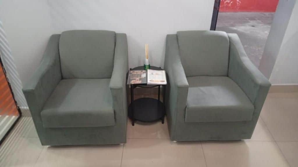 Two armchairs facing each other with a small table between them, a bottle, and a menu on the table.