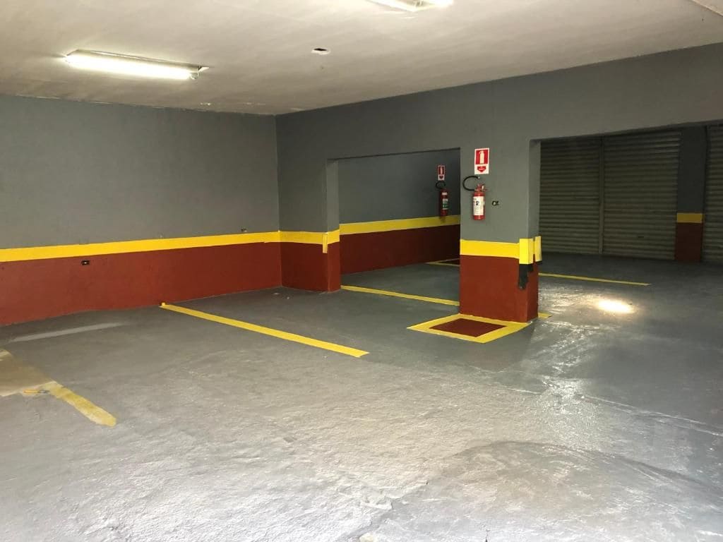 Un aparcamiento con plazas delimitadas, extintor y puerta de garaje cerrada.