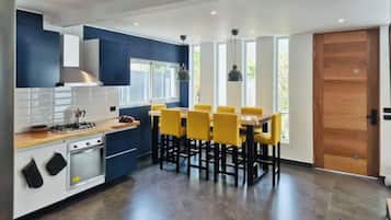 Een moderne keuken met een eethoek, voorzien van een fornuis, oven en gele stoelen.